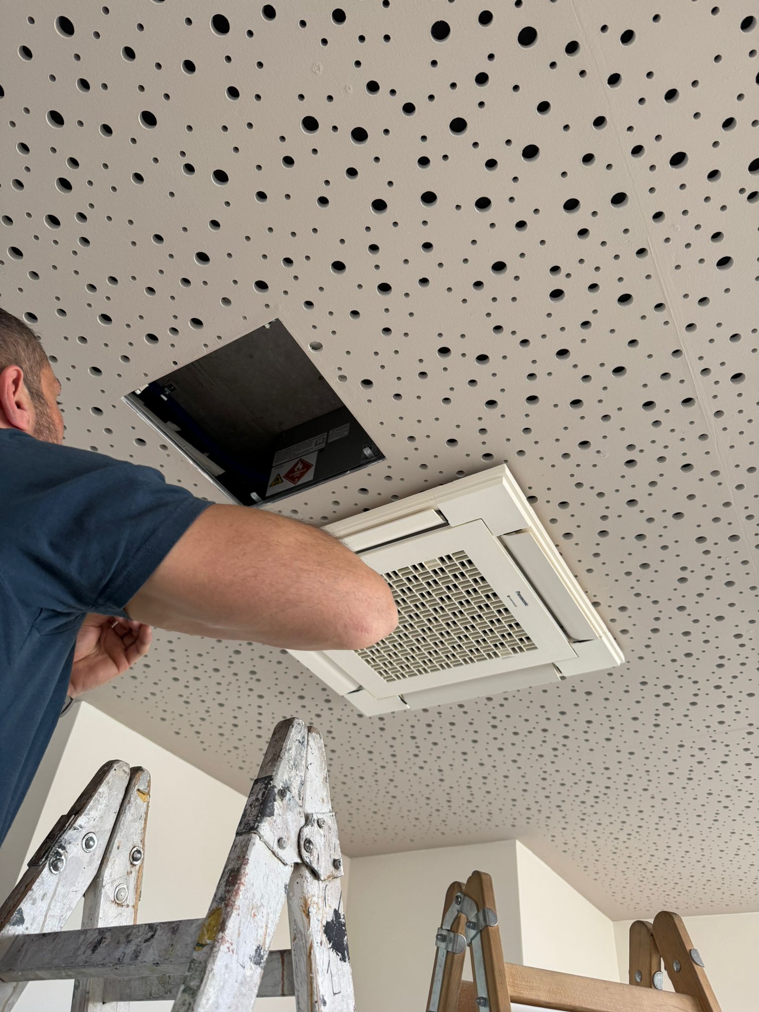 Monteur bei der Montage eines Klima-Innengeräts an der Decke